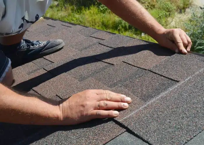 Roofer checking the condition of asphalt shingles